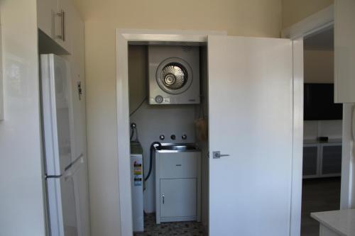 a kitchen with a refrigerator and a clock on the wall at Beaches Serviced Apartments in Nelson Bay