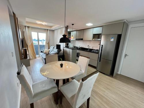 a kitchen and living room with a table and chairs at Lindo apartamento no centro de Canoas in Canoas