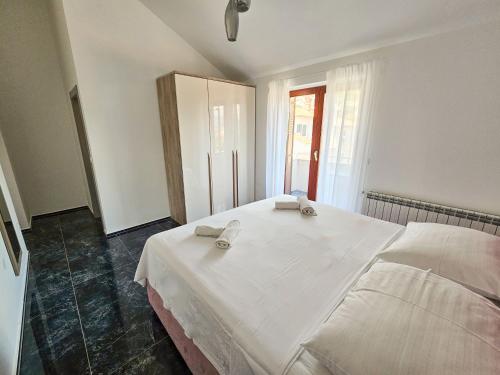 a bedroom with a white bed with towels on it at Rooms Tanja Lovran in Lovran
