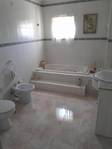 een badkamer met een bad, een toilet en een wastafel bij You have to love Amarante in Amarante