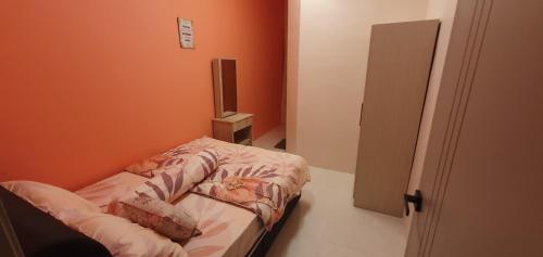 a small bed in a room with orange walls at Idaman villa homestay in Batu Gajah