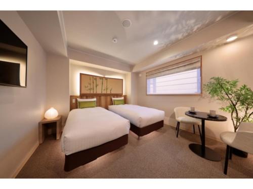 a bedroom with two beds and a table and a window at Gion Crystal Hotel - Vacation STAY 21885v in Kyoto