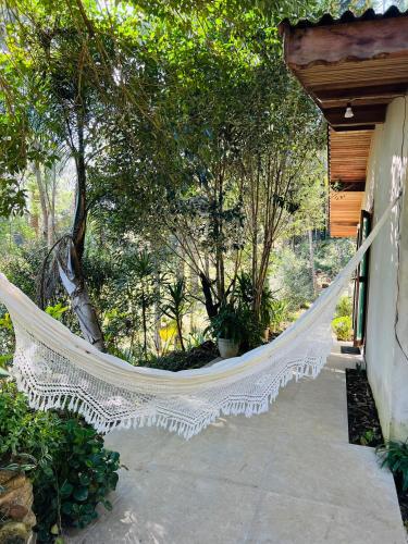 a white hammock hanging from a porch with trees at Quarto/suíte com lareira in São Miguel da Serra
