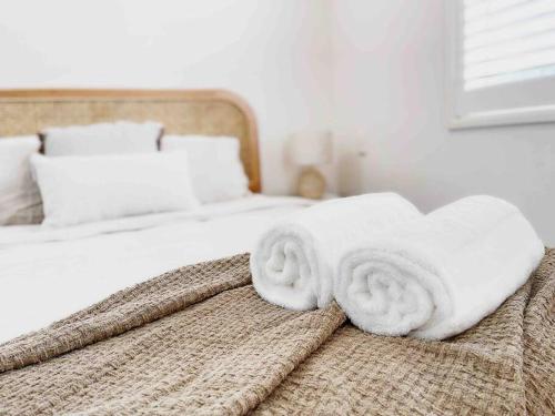 a bed with white towels on top of it at Palm Rest - 2BR Beachside Escape On Towradgi Beach in Towradgi