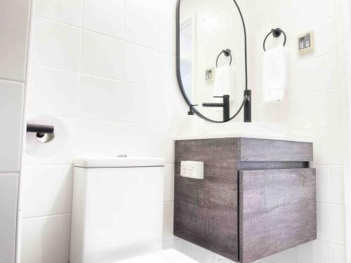 a bathroom with a toilet and a mirror at Palm Rest - 2BR Beachside Escape On Towradgi Beach in Towradgi