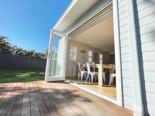 an open door to a patio with a table and chairs at Palm Rest - 2BR Beachside Escape On Towradgi Beach in Towradgi