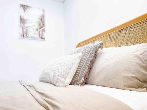 a bed with white sheets and pillows on it at Palm Rest - 2BR Beachside Escape On Towradgi Beach in Towradgi