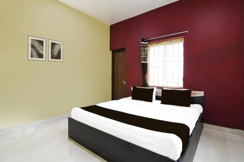 a bedroom with a large bed with a red wall at Super Hotel O MNJ Mansion in Bhubaneshwar