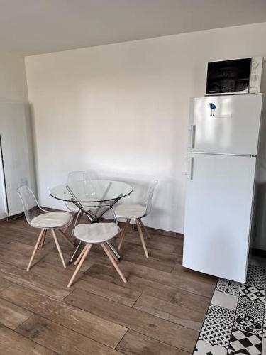 une cuisine avec une table, des chaises et un réfrigérateur dans l'établissement Maison de ville, à Montceau-les-Mines