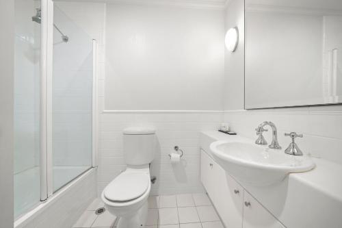 a white bathroom with a toilet and a sink at Comfort Apartments Melbourne Central in Melbourne