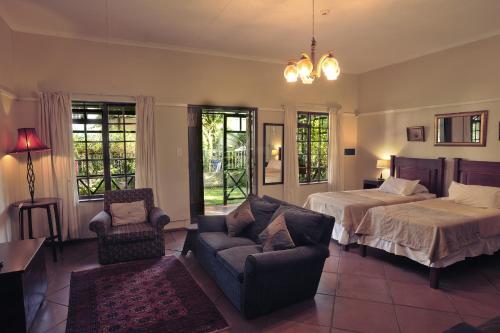 a bedroom with a bed and a couch and a bed and a chair at Petal Faire Cottage in Pretoria