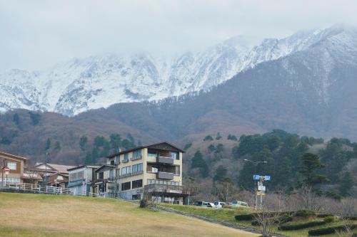 a building on a hill with mountains in the background at ITADAKI Daisen 大山参道ホテル頂 in Daisen