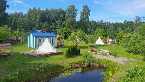 a group of tents in a field with a pond at Glamping Fluffy Horns - Glempings Pūkainie Ragi in Plieņciems