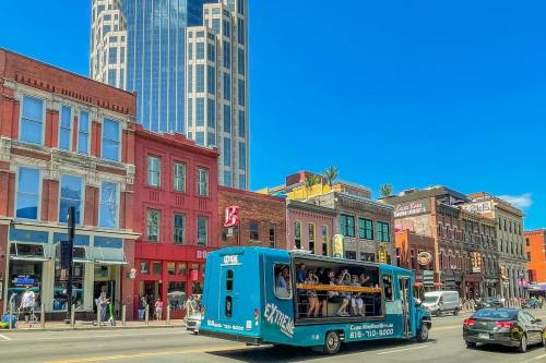 a blue bus driving down a city street with buildings at Grand Loft ON THEE Broadway Strip in Nashville