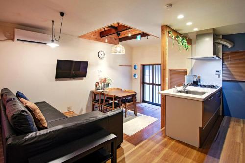 a living room with a couch and a kitchen with a sink at 旅タイム 住吉晴空 - 住吉大社周辺 in Osaka