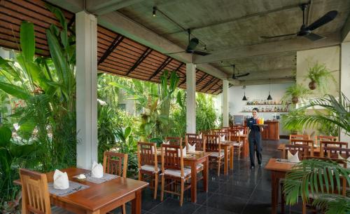 a restaurant with wooden tables and chairs and a person at Khmer House Boutique in Siem Reap