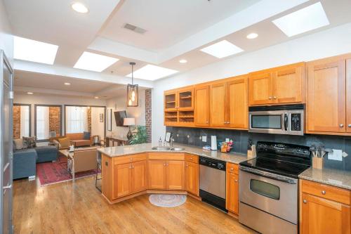 a kitchen with wooden cabinets and a living room at Spacious Penthouse ON the Broadway Strip in Nashville