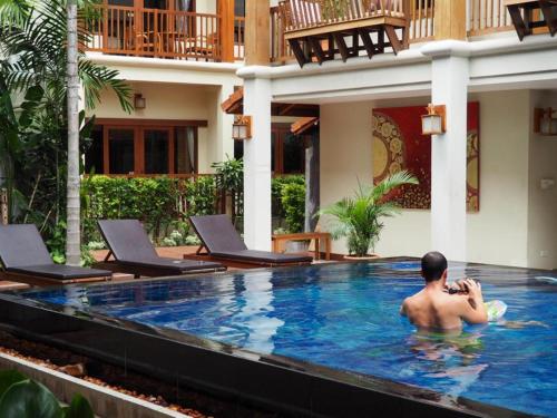 a man sitting in the swimming pool of a hotel at Vieng Mantra Hotel in Chiang Mai