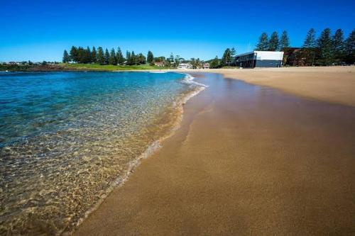 a view of a beach with a building in the background at Hills View BnB Studio Kiama Heights in Kiama