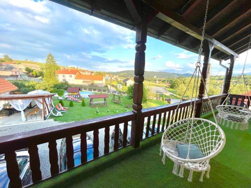a porch with swings and a view of a yard at Pensiunea Beatrice in Întorsura Buzăului