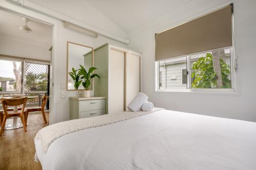 a white bedroom with a large bed and a table at BIG4 Tasman Holiday Parks - Ballina in Lennox Head