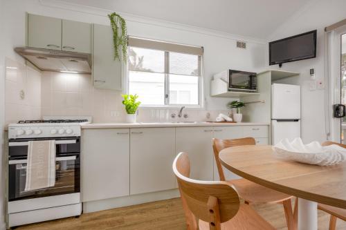 a kitchen with white cabinets and a wooden table at BIG4 Tasman Holiday Parks - Ballina in Lennox Head