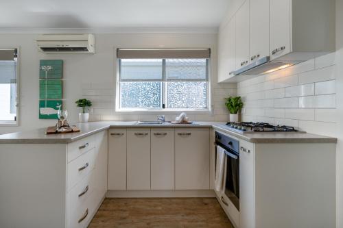 a kitchen with white cabinets and a stove top oven at BIG4 Tasman Holiday Parks - Ballina in Lennox Head