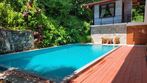 a swimming pool with a wooden deck next to a house at Pinnacle of Everything in Kandy