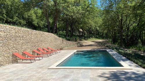 a swimming pool with lounge chairs and a brick wall at Santonne in Apt