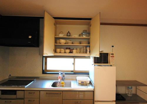 a small kitchen with a sink and a refrigerator at 家主居住型 那須のレジャー施設が楽しめる若草邸 in Nasushiobara