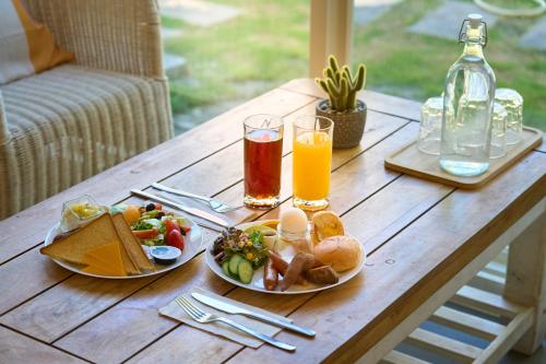 a table with two plates of food and two glasses of orange juice at OwlStay Green Villa in Pinghe