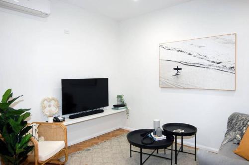 a living room with a tv on a white wall at Coastal Nest - Stylish 1BR Steps to Towradgi Beach in Towradgi