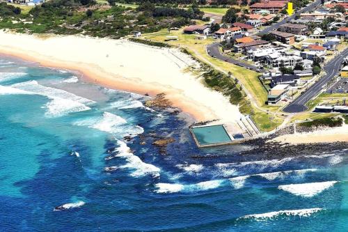 an aerial view of a beach and the ocean at Coastal Nest - Stylish 1BR Steps to Towradgi Beach in Towradgi