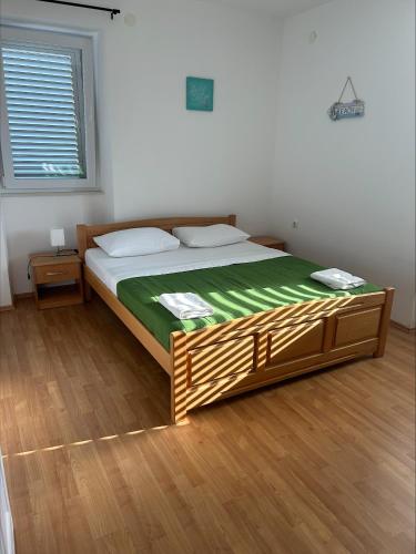 a bedroom with a bed with a green blanket on it at Beach House Murter in Murter