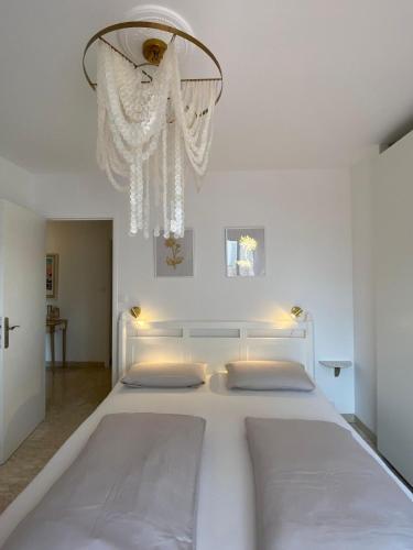 - un lit blanc dans une chambre blanche dotée d'un lustre dans l'établissement Sanary- La vie est belle- Centre Ville 2 minutes à pied- Plage 5 minutes, à Sanary-sur-Mer