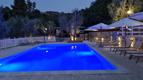 a swimming pool at night with tables and umbrellas at Village Valle D'Oro ApartHotel in San Menaio
