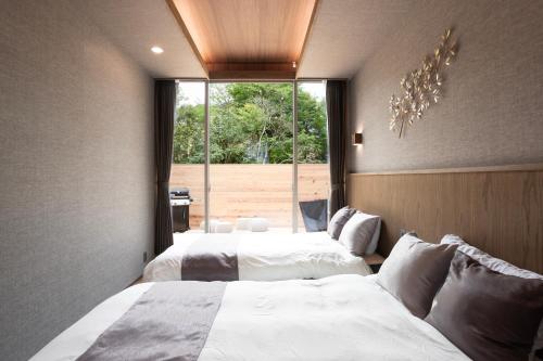 a bedroom with two beds and a large window at Smart Villa Hakone Gora - Smart Villa 箱根強羅 in Hakone