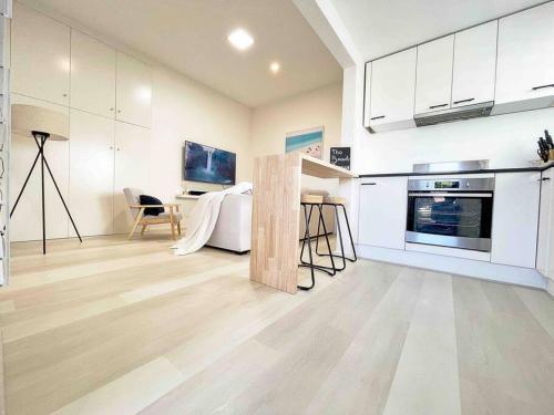 TowradgiにあるThe Beach Pad - Renovated 1BR Steps from Towradgiの白いキャビネットとテーブル付きのキッチンが備わります。