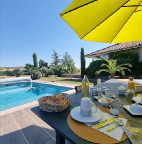 a table with a yellow umbrella next to a swimming pool at Relais de navon in Saint-Joseph