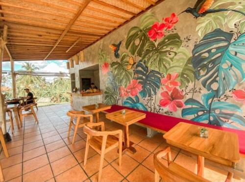 a restaurant with tables and a mural of flowers on the wall at Eka Dwi Guest House in Gianyar