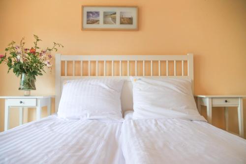 a bed with white sheets and a vase with flowers on it at Laguna Resort in Budzisław