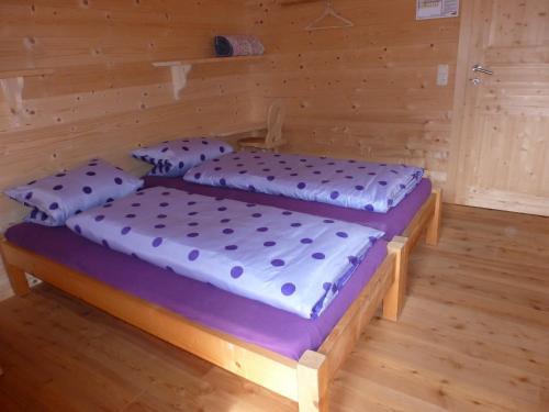 two beds in a room with wooden walls at Binsalm- Schutzhütte in Vomp