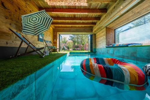 Cette maison dispose d'une piscine avec une chaise et un parasol. dans l'établissement Chalet ORION Serre-chevalier piscine cinéma, au Monêtier-les-Bains