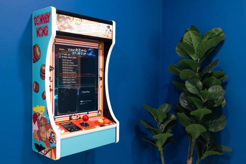 a pinball machine on a blue wall with a plant at The Mariners Rest, Near Downtown, Savannah Coastal Charm in Savannah