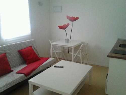a living room with a couch and a table with two roses at Camping Playa Sauces in Ribadesella