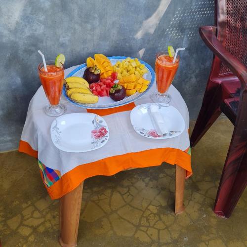 a table with a tray of fruit and drinks on it at Charly Villa in Haburugala