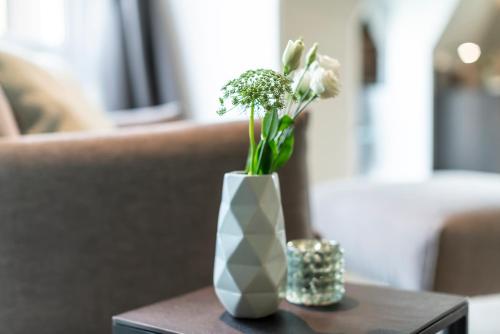 a white vase with white flowers on a table at Hotel Sonne in Rheda-Wiedenbrück