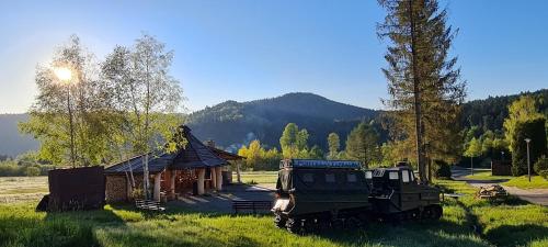a military vehicle parked in a field next to a building at Perełka Bieszczady Domki in Cisna