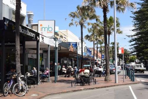 a city street with people sitting at tables on a sidewalk at Hills View BnB Studio Kiama Heights in Kiama