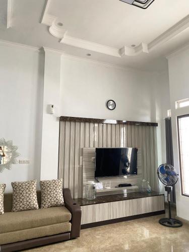 a living room with a couch and a flat screen tv at Villa Hasanah in Subang